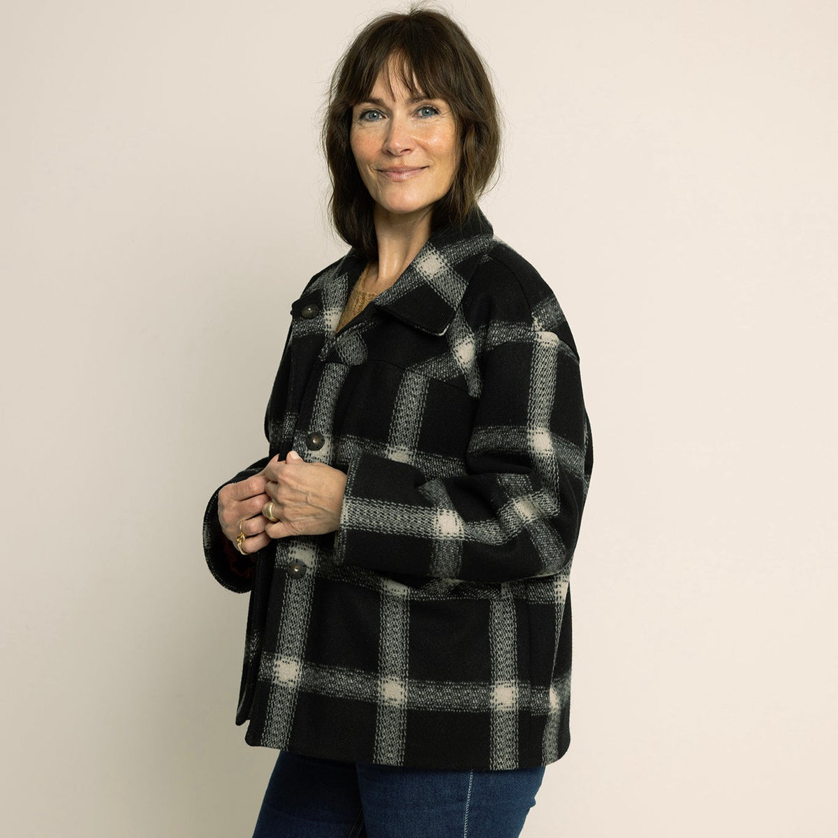 Woman wearing a black and gray checkered coat against a plain background